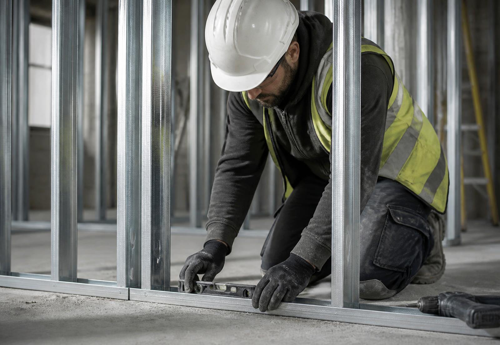 An experienced installer setting out metal stud framing on a construction site
