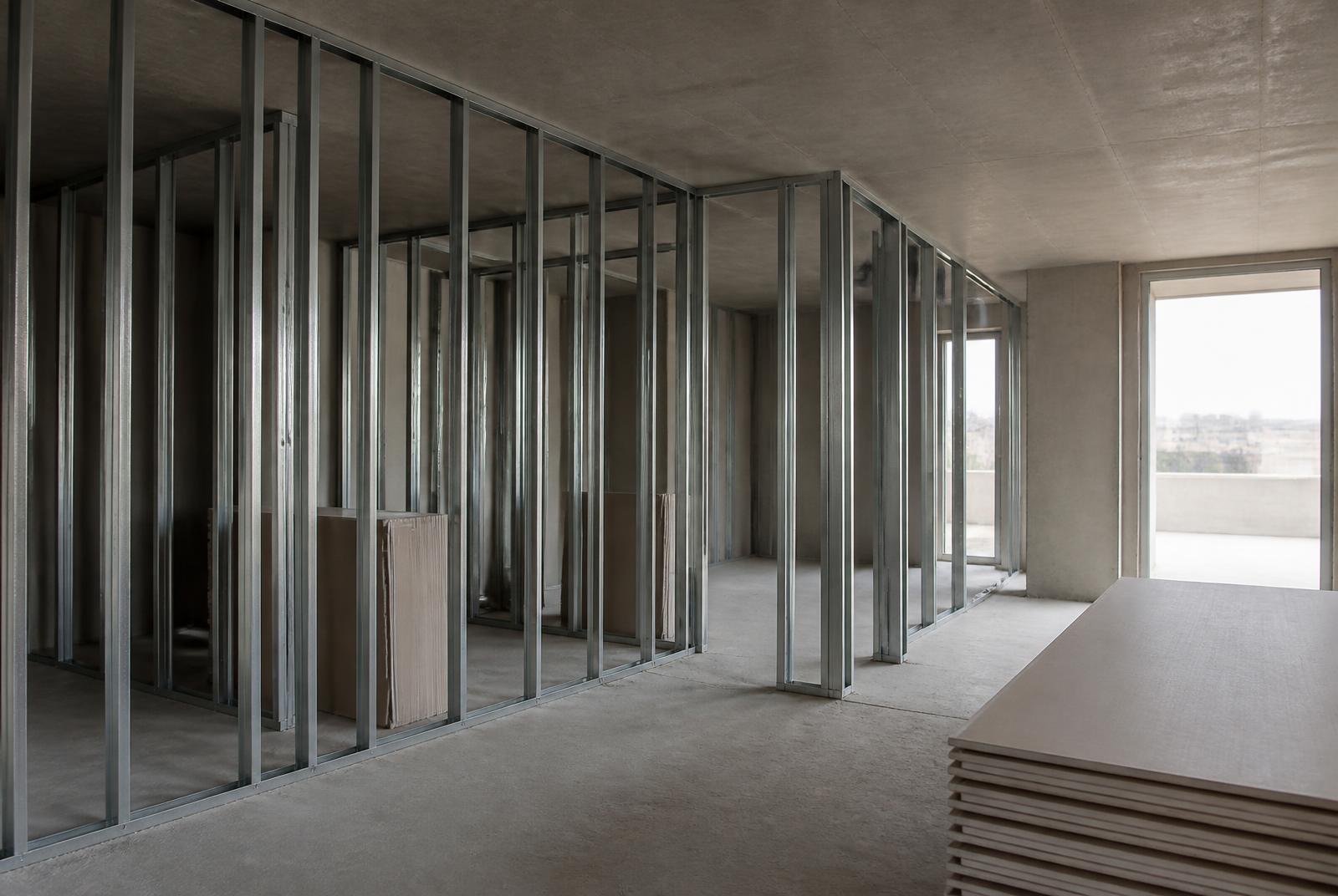 Metal stud partitions and stacked plasterboard within an apartment shell during fit-out
