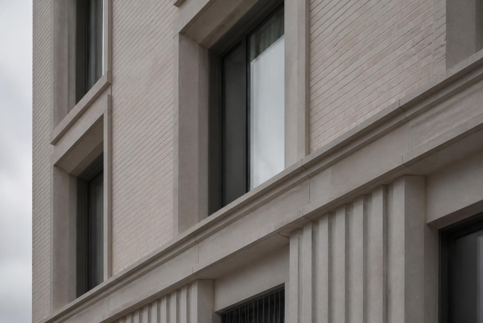 Close detail of the facade showing the junction between brickwork and cast stone banding