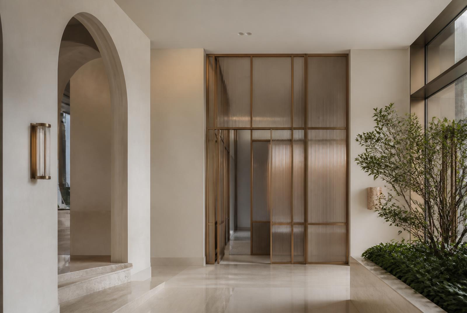 Completed residential lobby with plaster walls, bronze-toned metalwork and glazed screens
