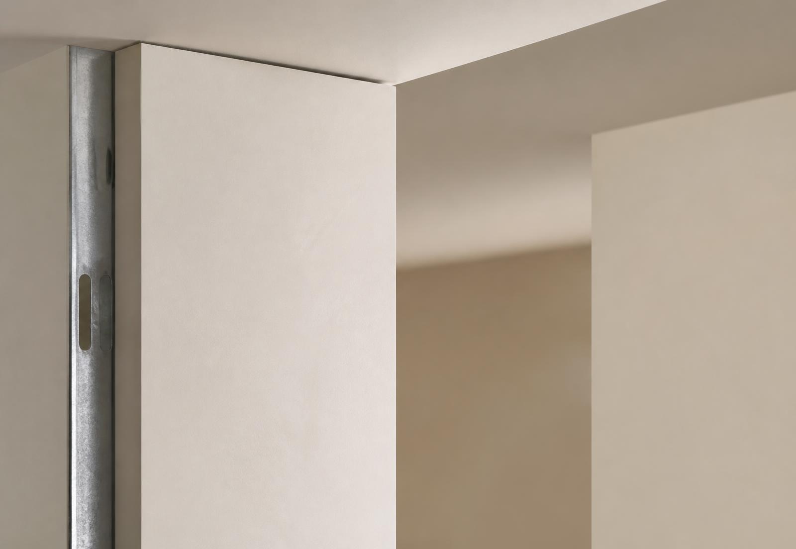 Close detail of a completed dry lining installation showing a metal stud edge and a flush plaster finish